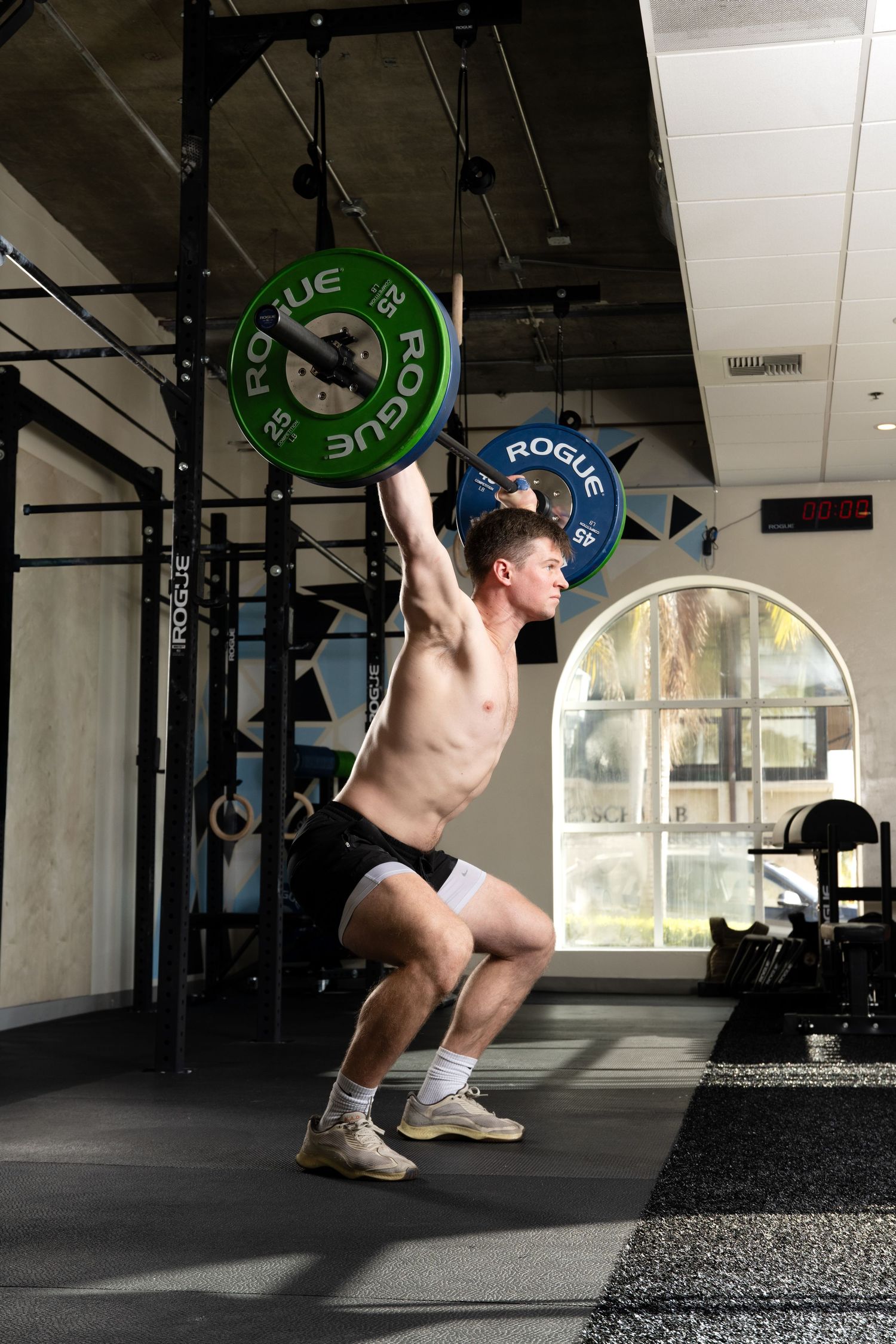 A sequence of weightlifting movements showing proper snatch technique with green weight plates in a gym setting.