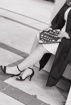 Close-up black and white photo of feet in heels on brick pavement.