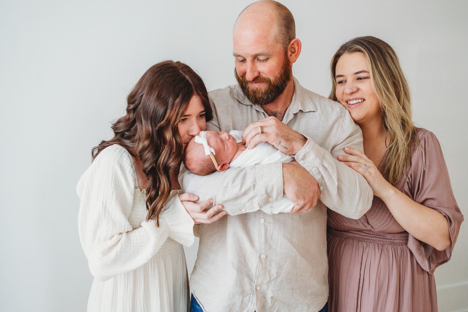 Family photo session with parents holding their newborn baby indoors.