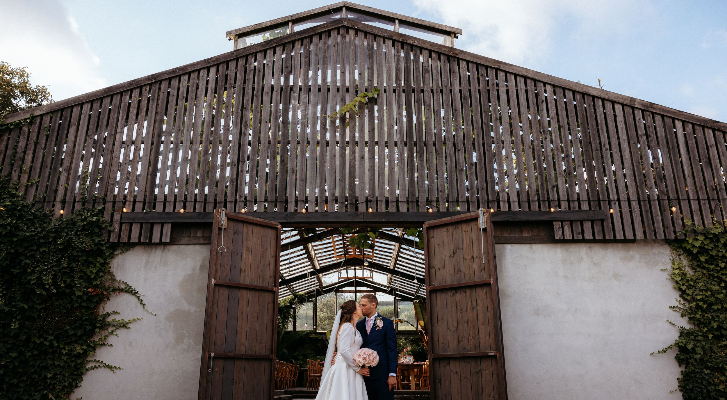Panoramic view of a rustic barn wedding venue with large wooden doors.