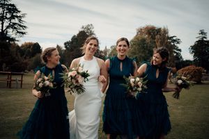 Wedding party poses together on a grassy lawn in front of a stately building.
