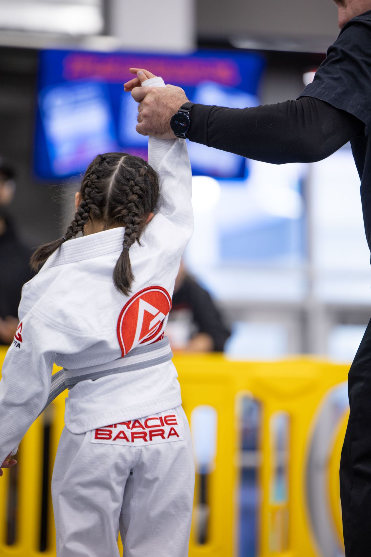 Competitor in white martial arts uniform with Gracie Barra logo at competition event.