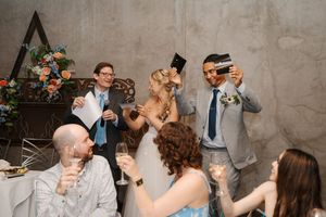 Wedding guests dance and celebrate together during a lively reception party at an industrial-style venue.