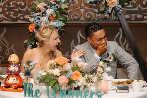 Wedding reception guests enjoy a candlelit dinner with elegant floral centerpieces and glowing table settings.