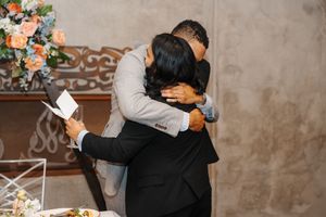 A couple shares a romantic moment during their wedding ceremony with floral decorations in the background.