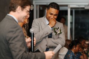 Wedding guests share a candid laugh during a joyful reception moment in a light-filled venue.