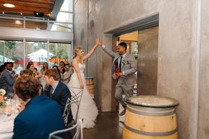 A panoramic view of a wine cellar tasting room with wooden barrels and people gathered for a celebration event.