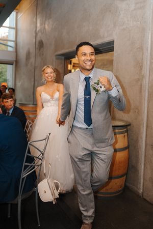 A couple dances and celebrates together at a rustic wedding venue with wine barrels in the background.
