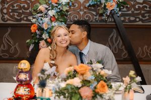 A romantic wedding reception moment at a decorated table with peach and blue floral arrangements.