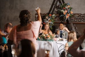 A joyful wedding celebration with people dancing and socializing under floral decorations in an elegant indoor venue.
