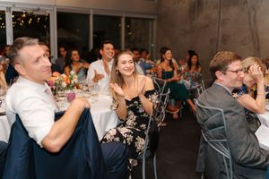 Wedding guests raise their glasses in celebration during a reception toast at an indoor venue.