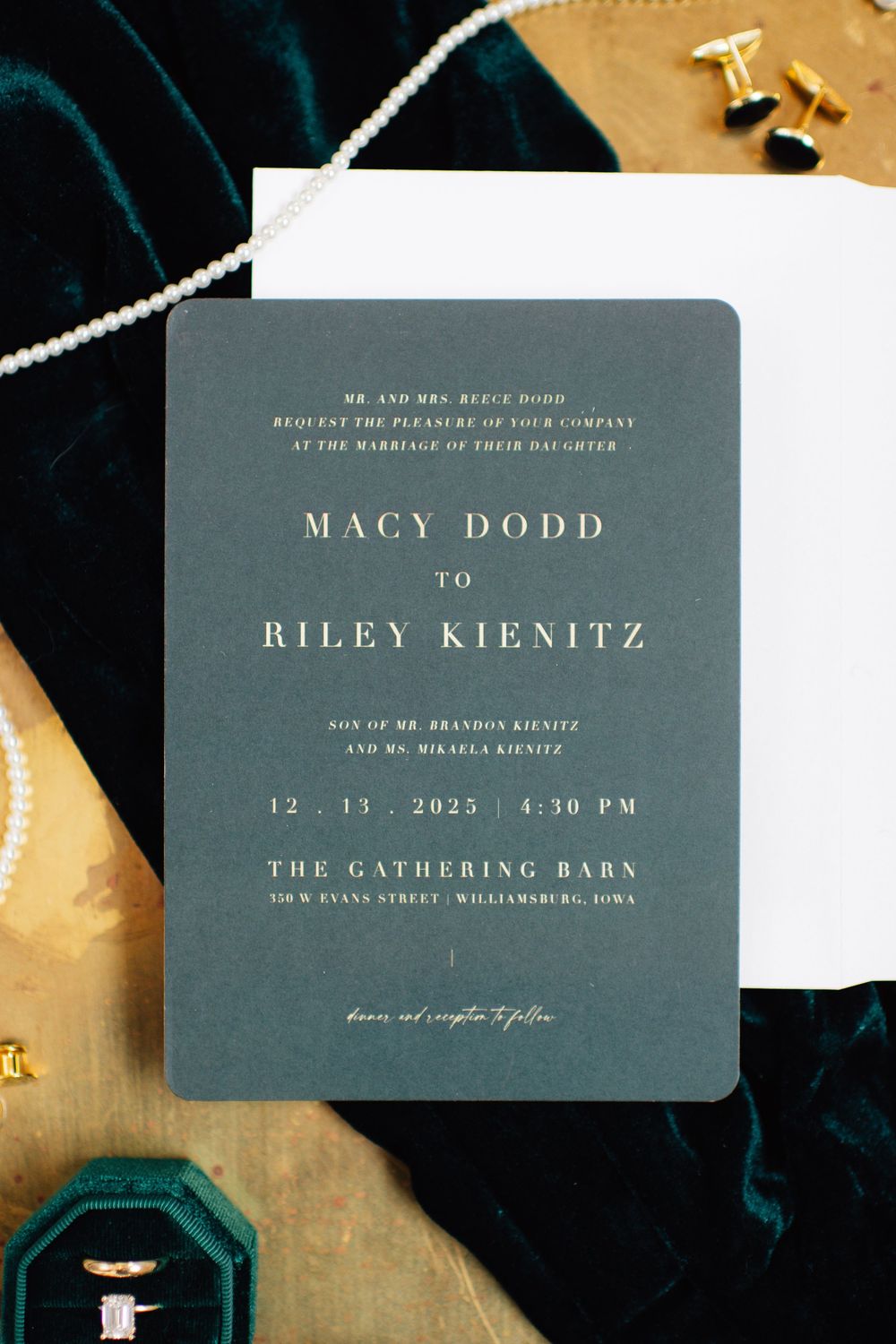 Elegant wedding invitation with dark green typography and gold details on textured background.
