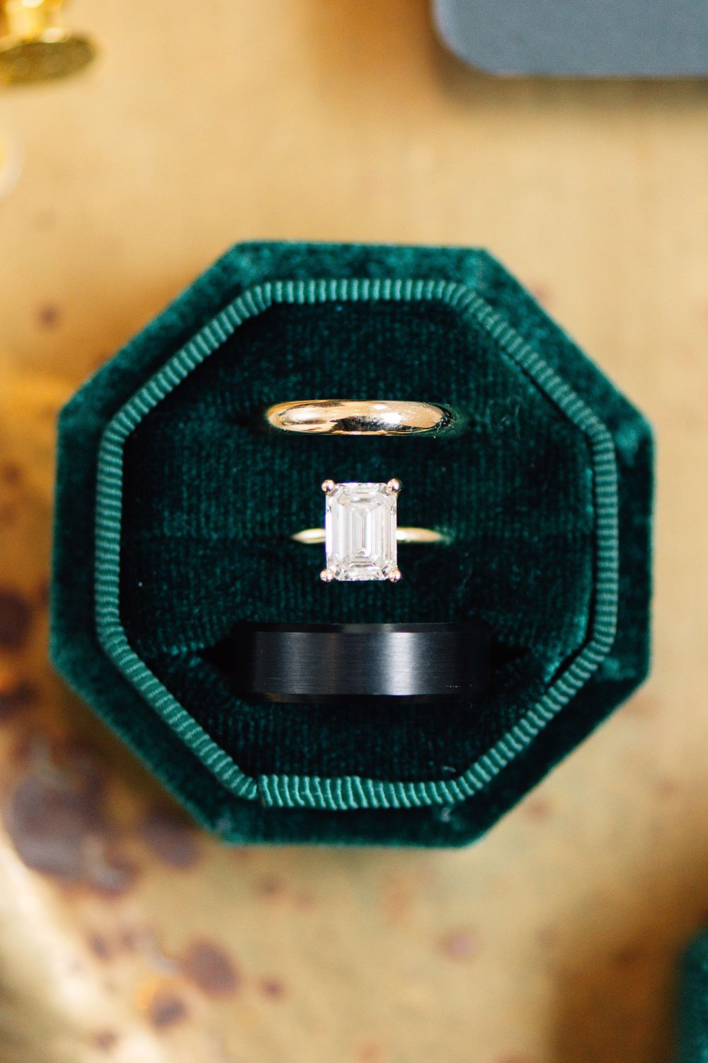 Elegant engagement ring with emerald cut diamond displayed in dark green velvet octagonal ring box.
