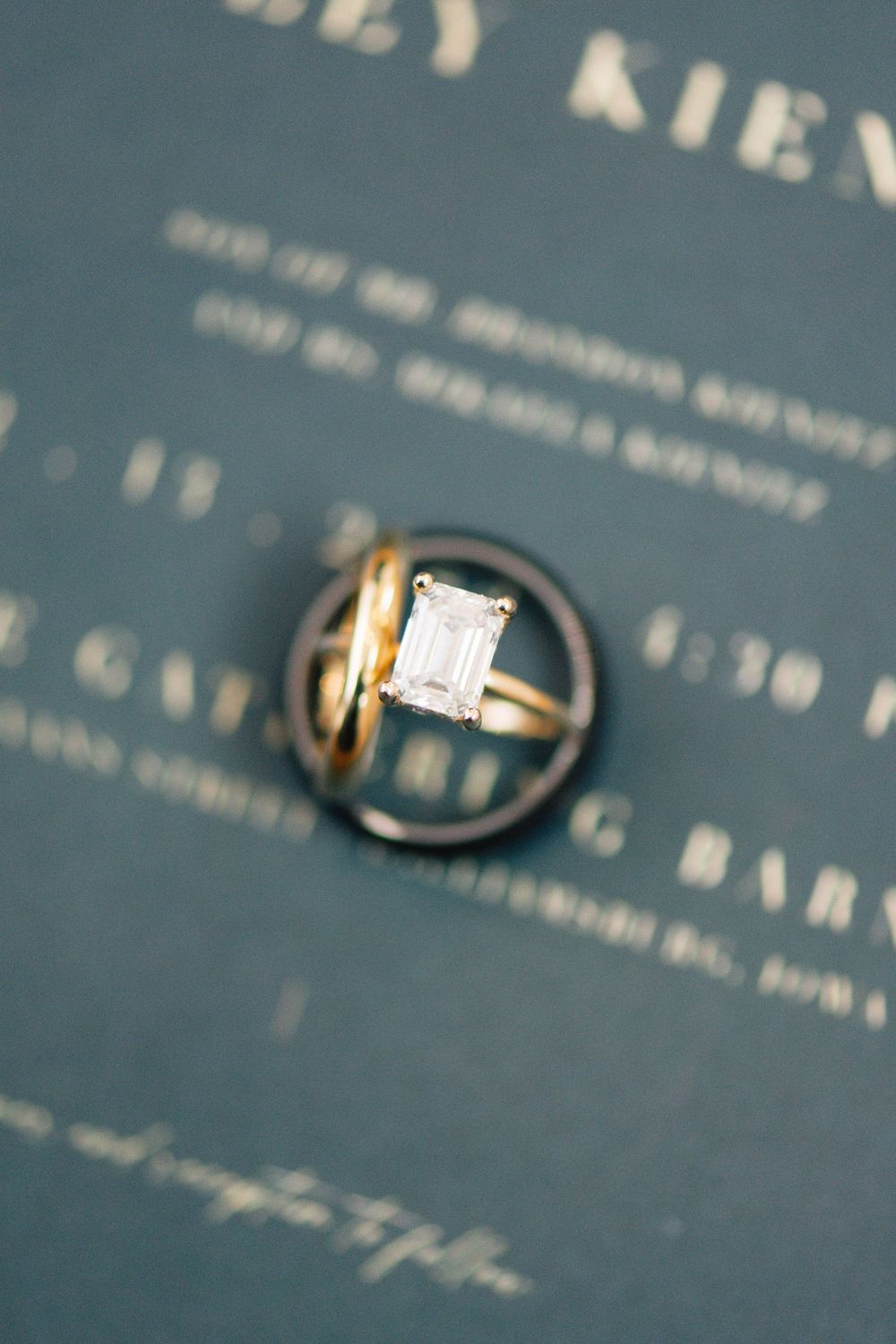 Close-up of diamond engagement ring photographed against blue textured background.