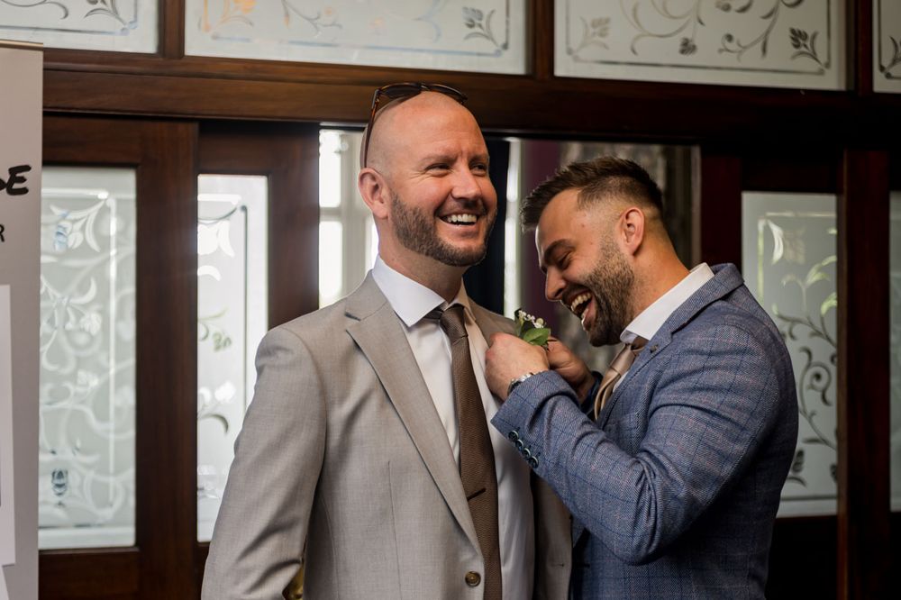 Wedding party members share a candid moment and laughter in a hallway.