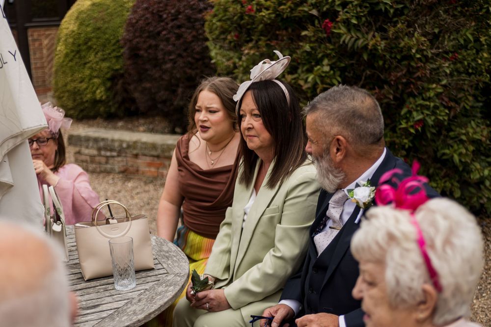 Wedding guests enjoy outdoor reception conversations in garden setting.