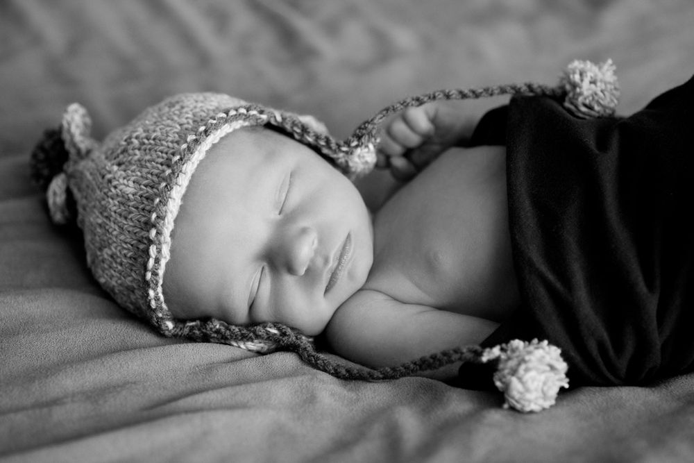 black and white photo of a newborn wearing a hat