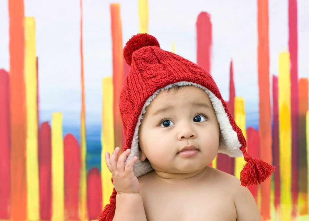 image of a baby wearing a red hat with a yellow and orange background