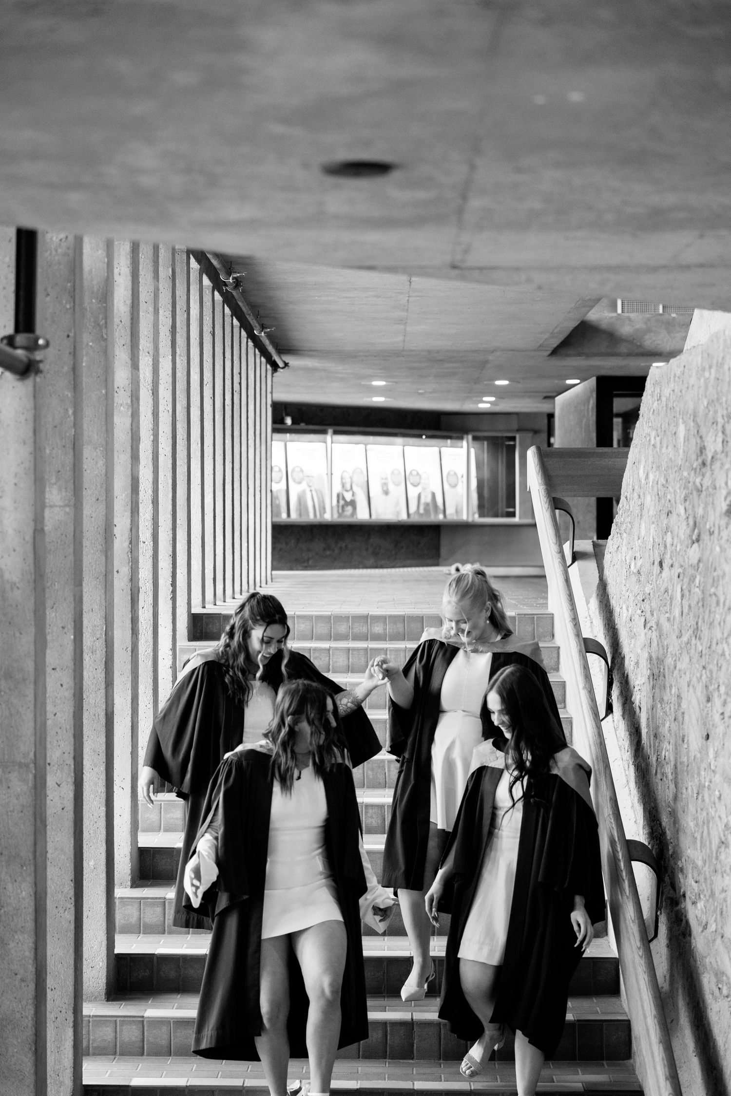 A black and white photo showing multiple people leaning against a concrete wall in a hallway.
