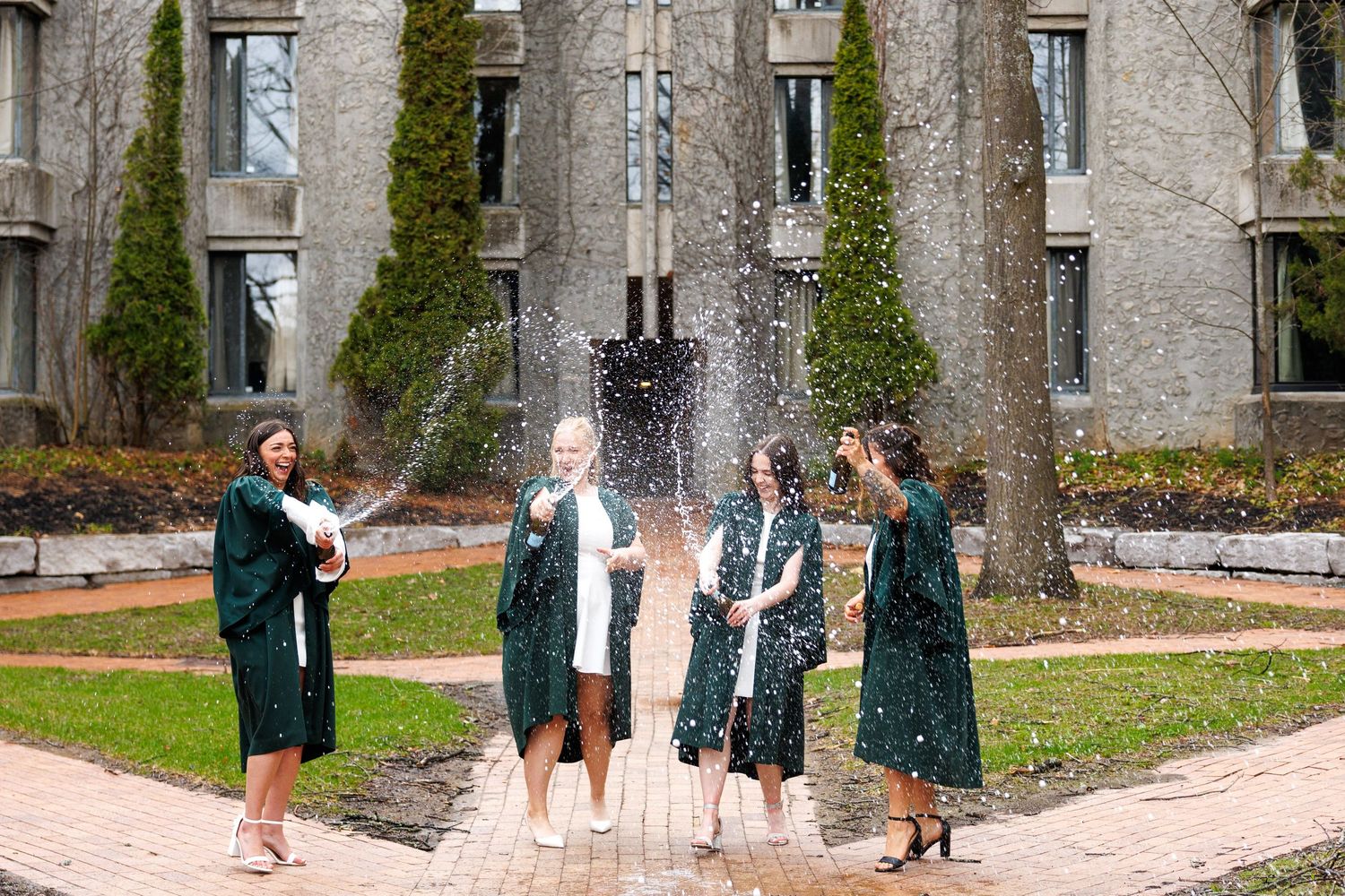 A series of five photos showing people playing a game with bowling pins outdoors at a historic stone building.