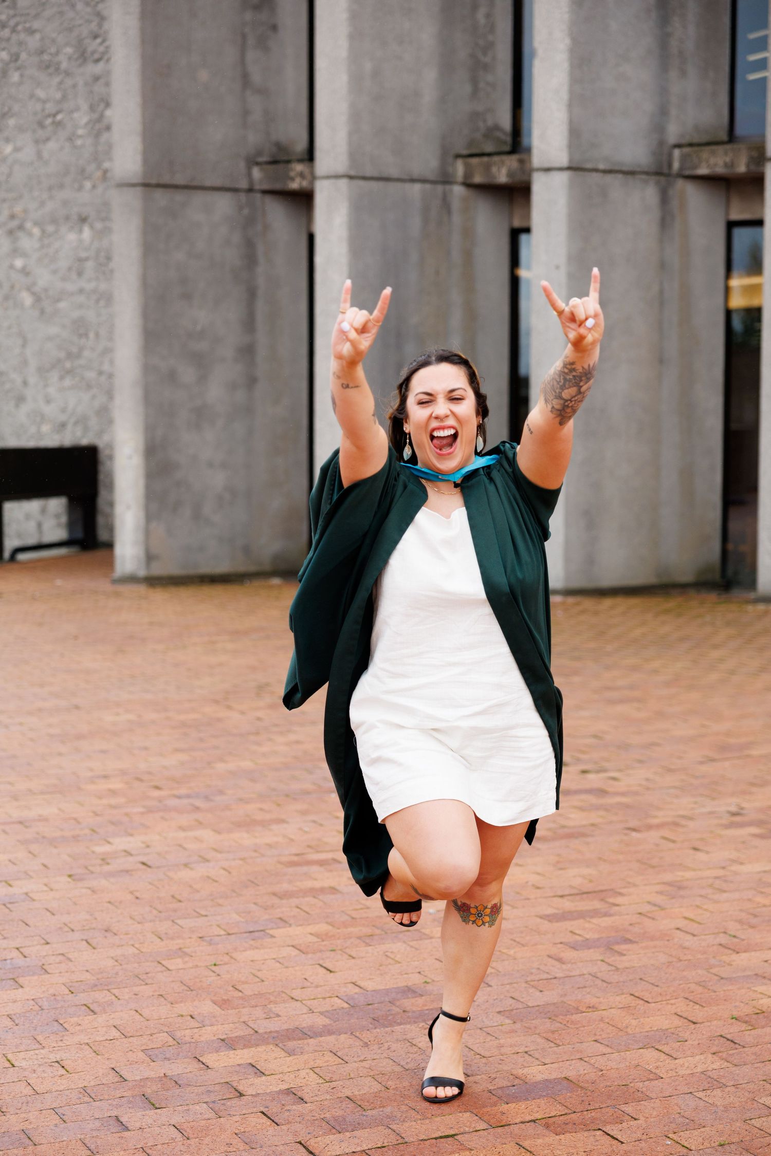 A series of photos showing someone in a green graduation gown jumping with excitement on brick pavement.
