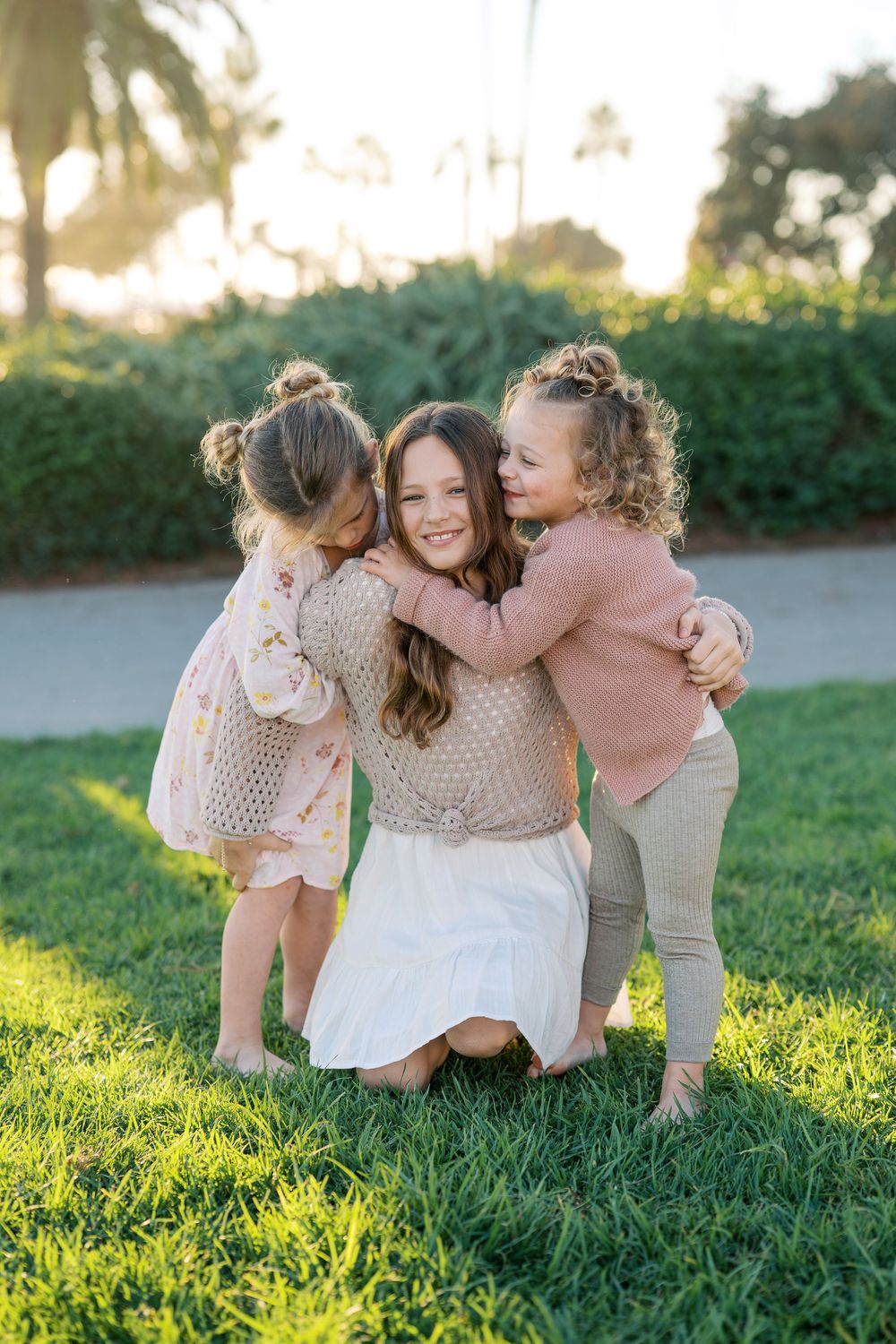 A loving family moment captured in golden sunlight while sitting together on green grass.