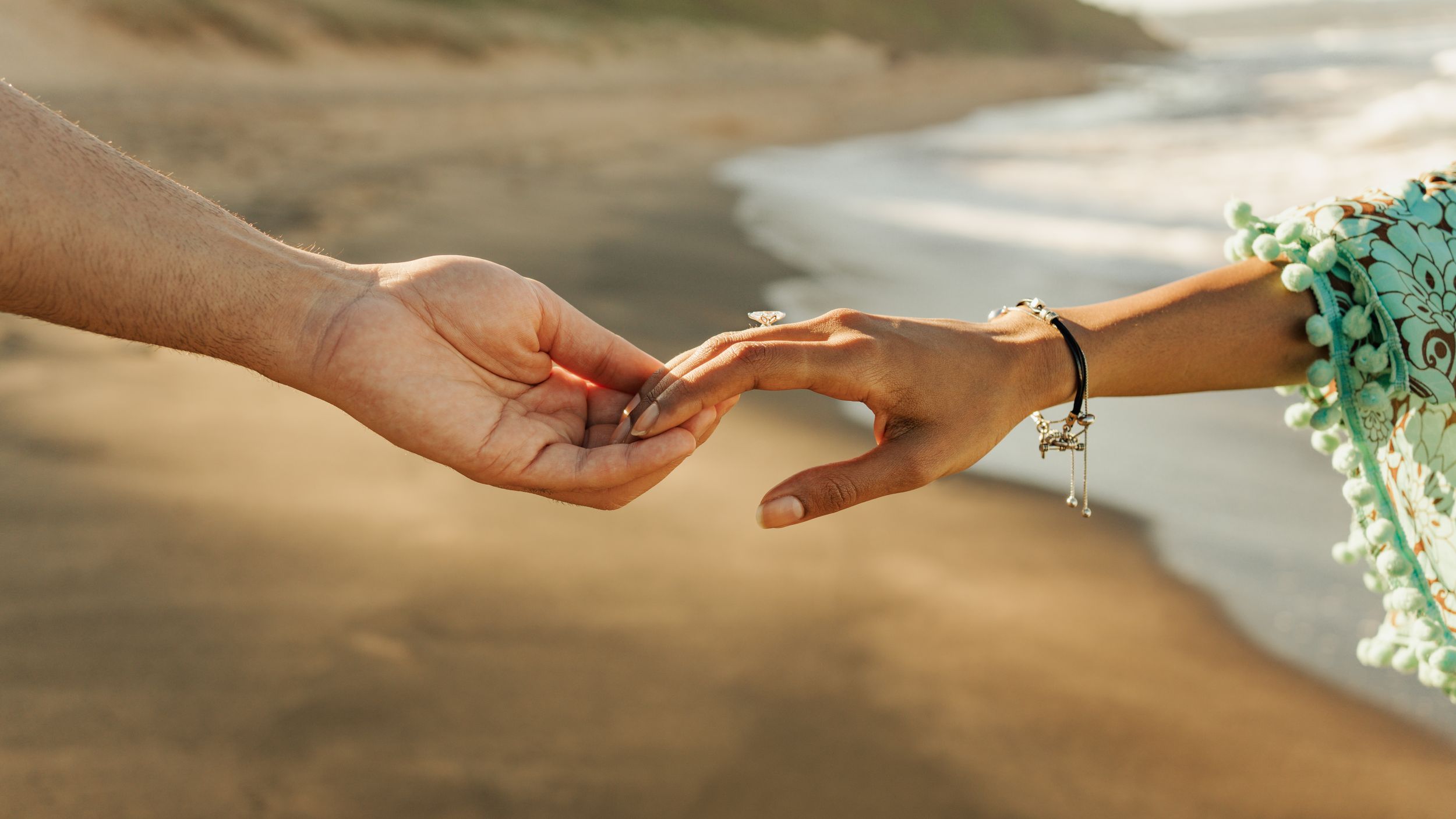 Hands exchanging wedding rings during an intimate outdoor ceremony with soft natural lighting and greenery in the background.