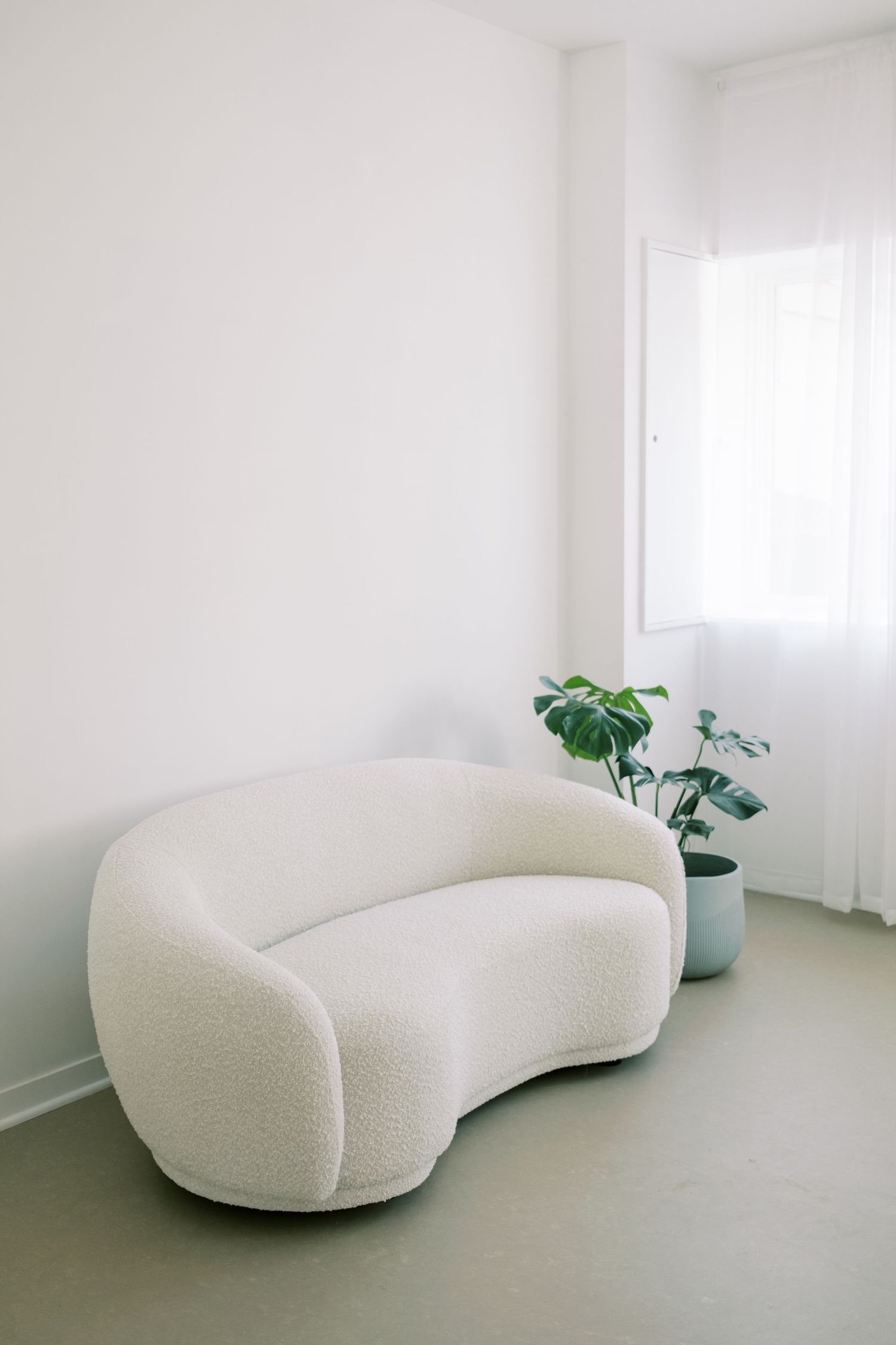 Photography studio setup with white backdrop and lighting equipment against a wall with natural window light.