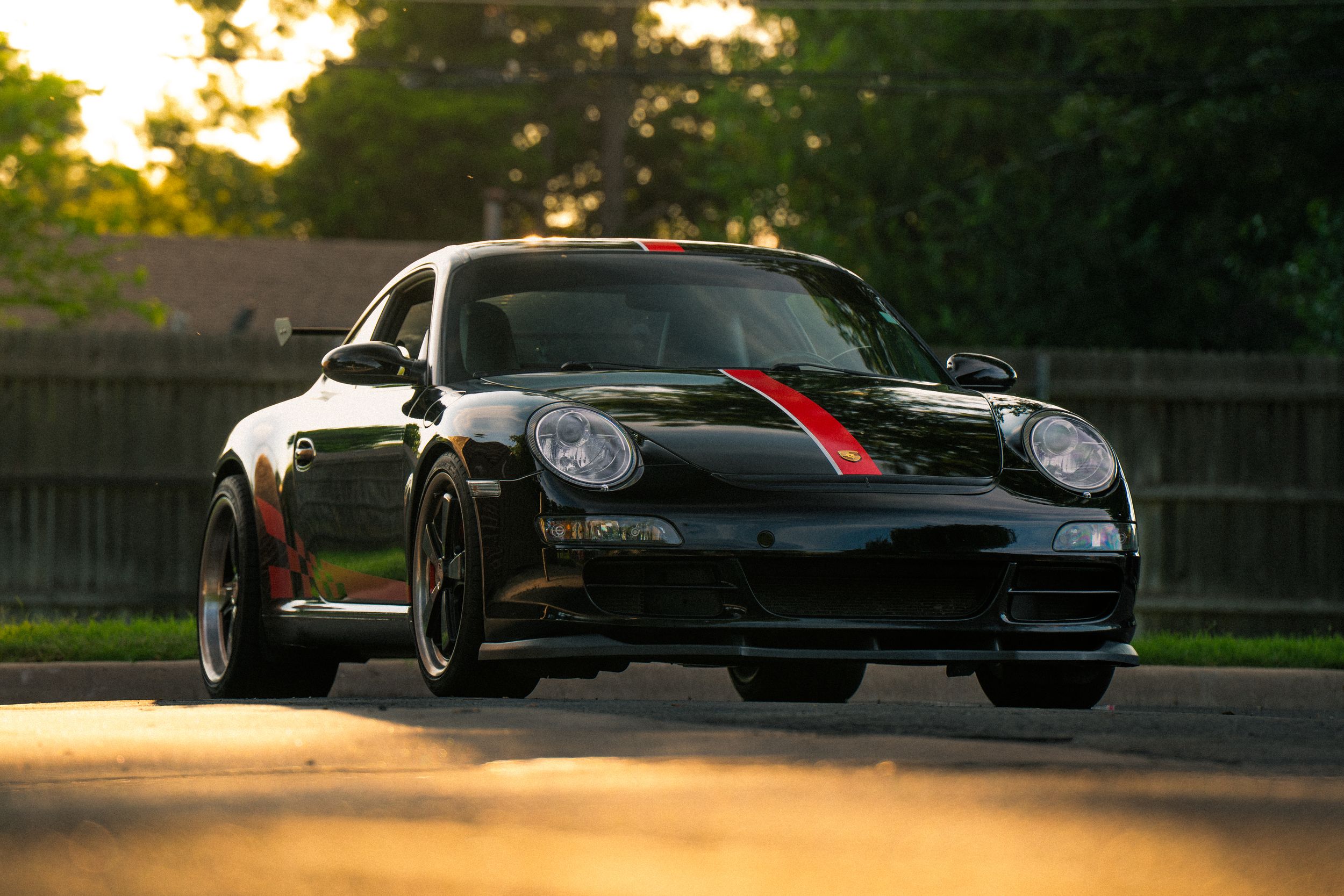 A black luxury sports car photographed at sunset with dramatic lighting and reflections.