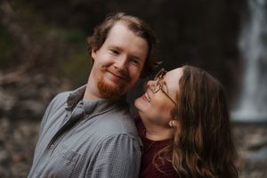 A couple shares tender moments during an outdoor photoshoot in a natural setting.