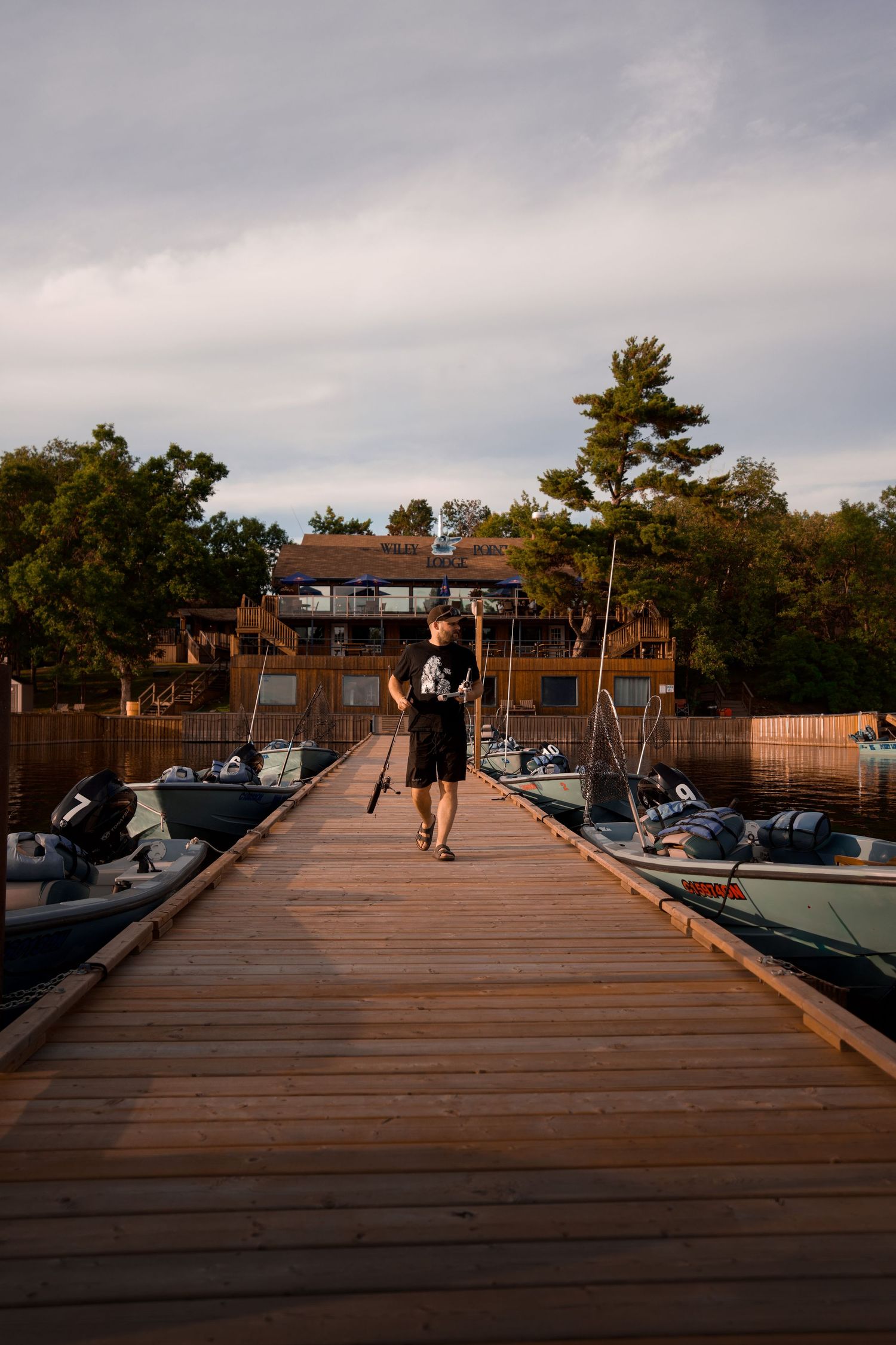 Wooden boat dock stretches into the distance under cloudy skies at dusk.