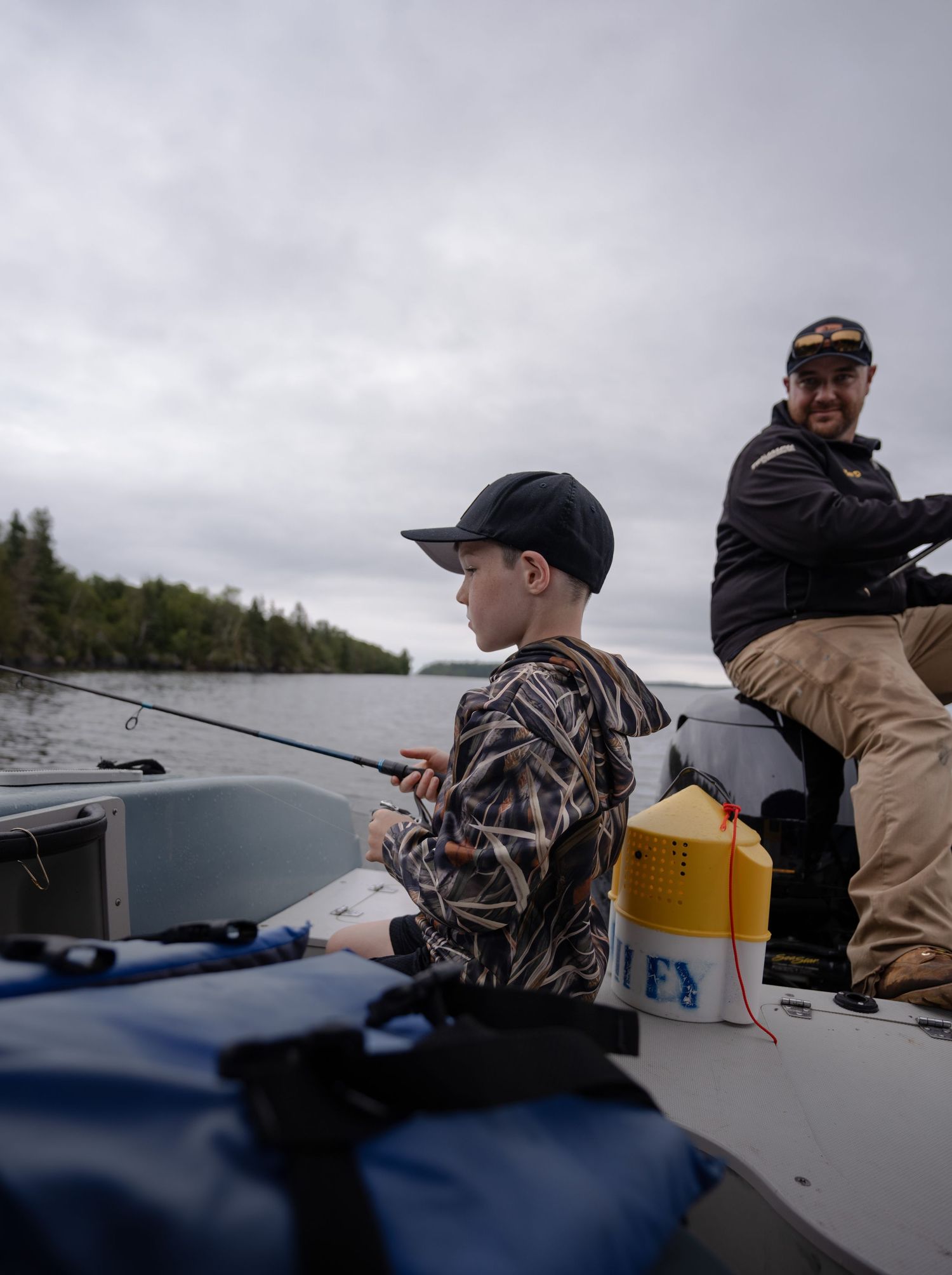 Anglers fishing from boats on a misty lake surrounded by forest.