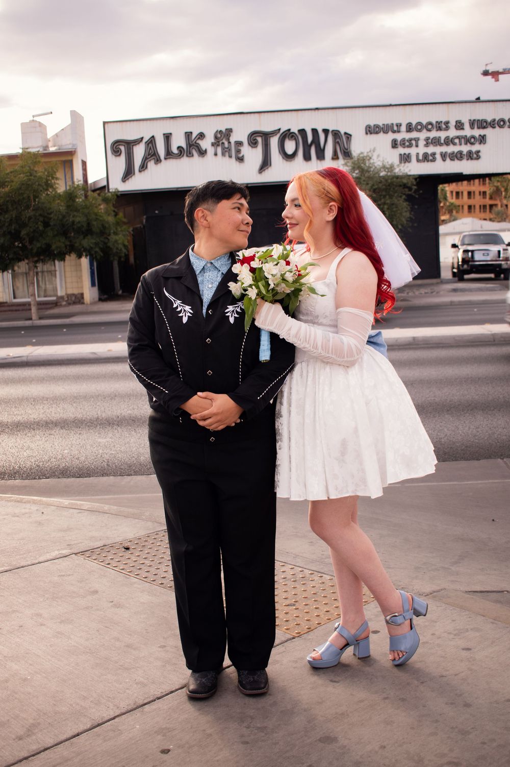 Talk of the Town Adult store sign behind couple at Little White Chapel Las Vegas wedding. Bride leaning on spouse LGBTQ