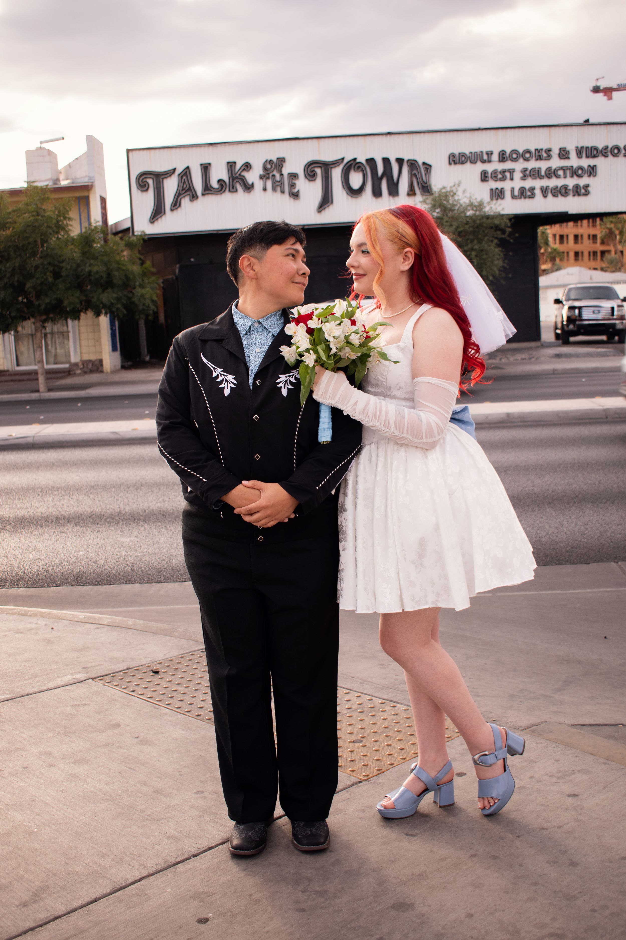 Talk of the Town Adult store sign behind couple at Little White Chapel Las Vegas wedding. Bride leaning on spouse LGBTQ