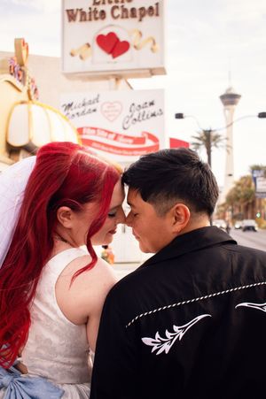 Close up of brides doing eskimo kiss with the Little White chapel sign in front of them