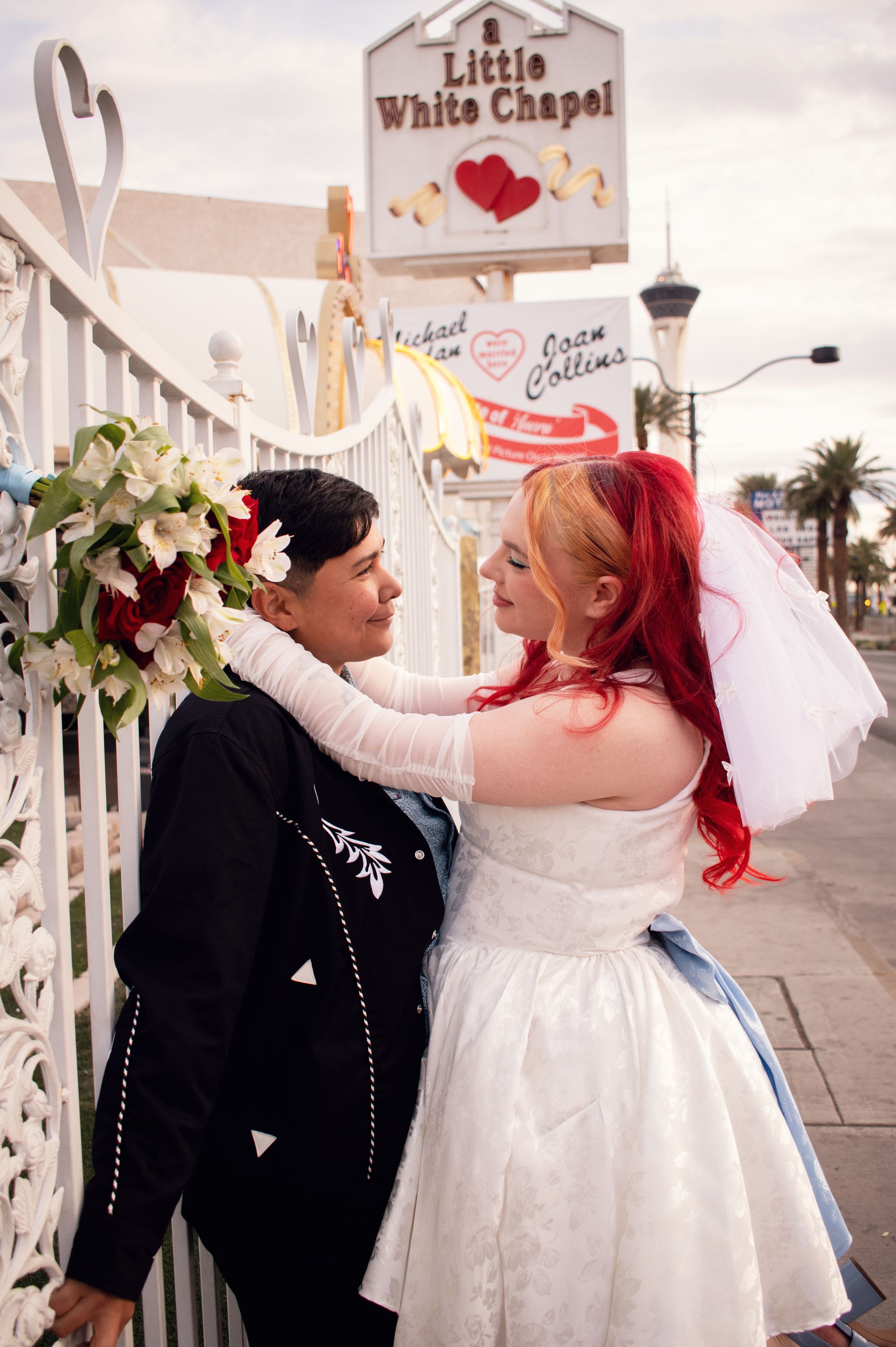 Little White Chapel Elopement LQBTQ couple leaning on gate into each other ready for a kiss