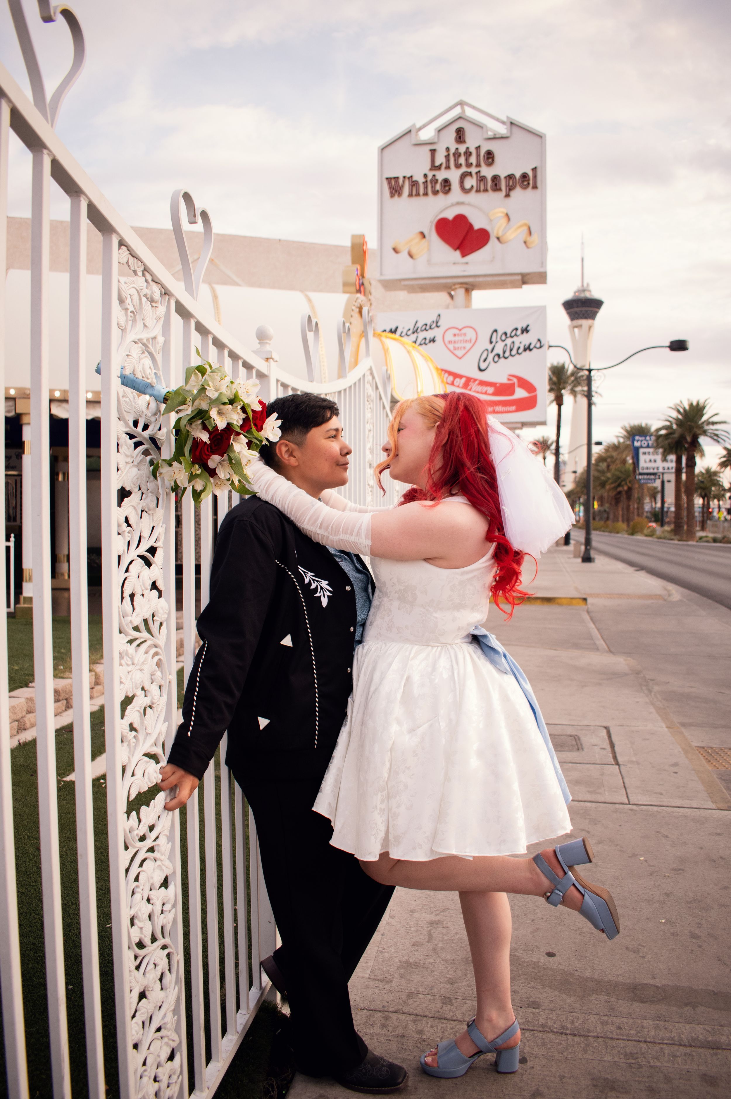 Little White Chapel Elopement LQBTQ couple leaning on gate into each other ready for a kiss