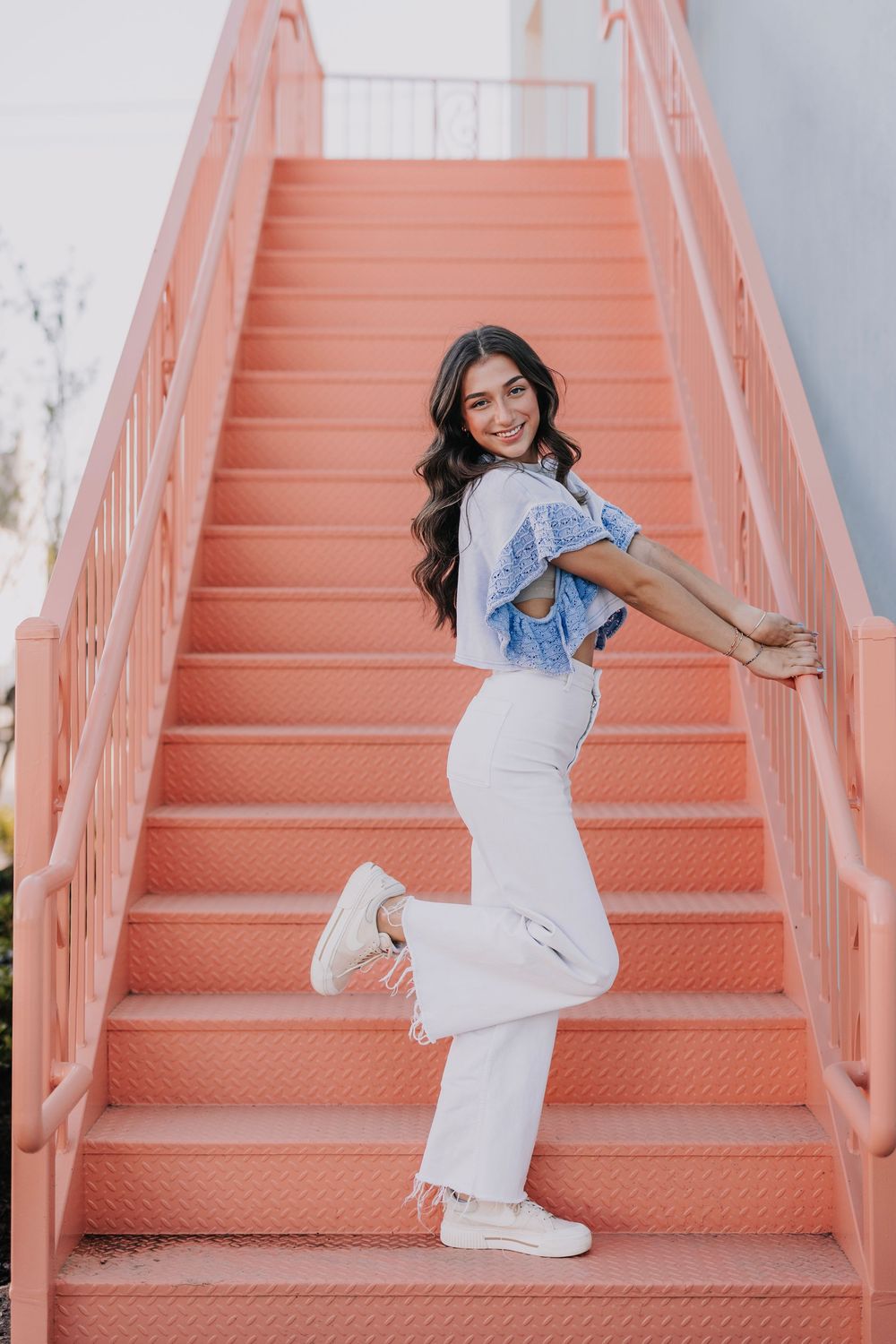 Lifestyle photoshoot on coral pink stairs with white and blue casual outfit.