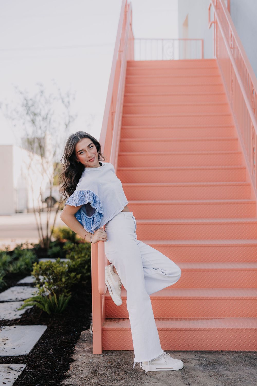 Casual fashion poses on peach-colored outdoor staircase.