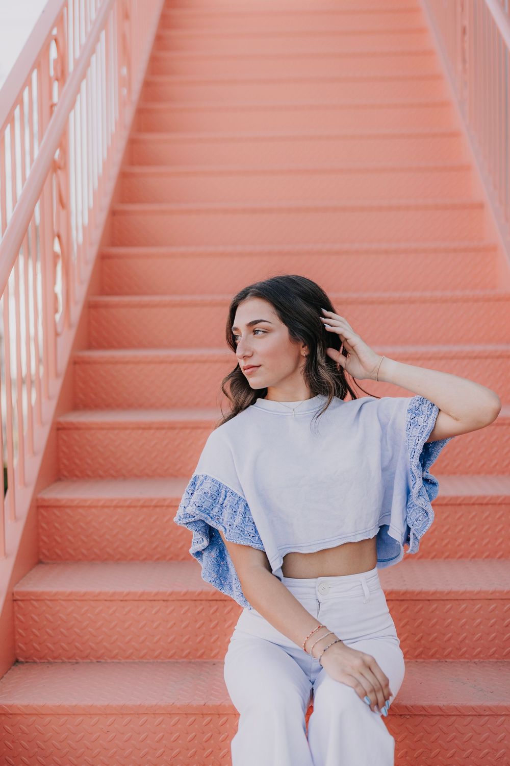 Portrait session featuring white crop top with blue ruffles against coral stairs.
