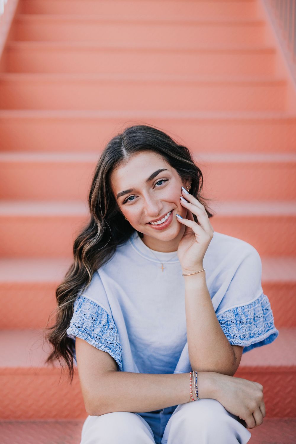 Casual fashion portraits on peach stairs wearing blue and white ensemble.