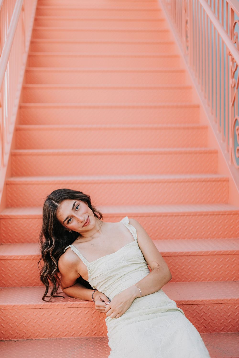 Artistic portrait series on coral pink stairs in light colored outfit.