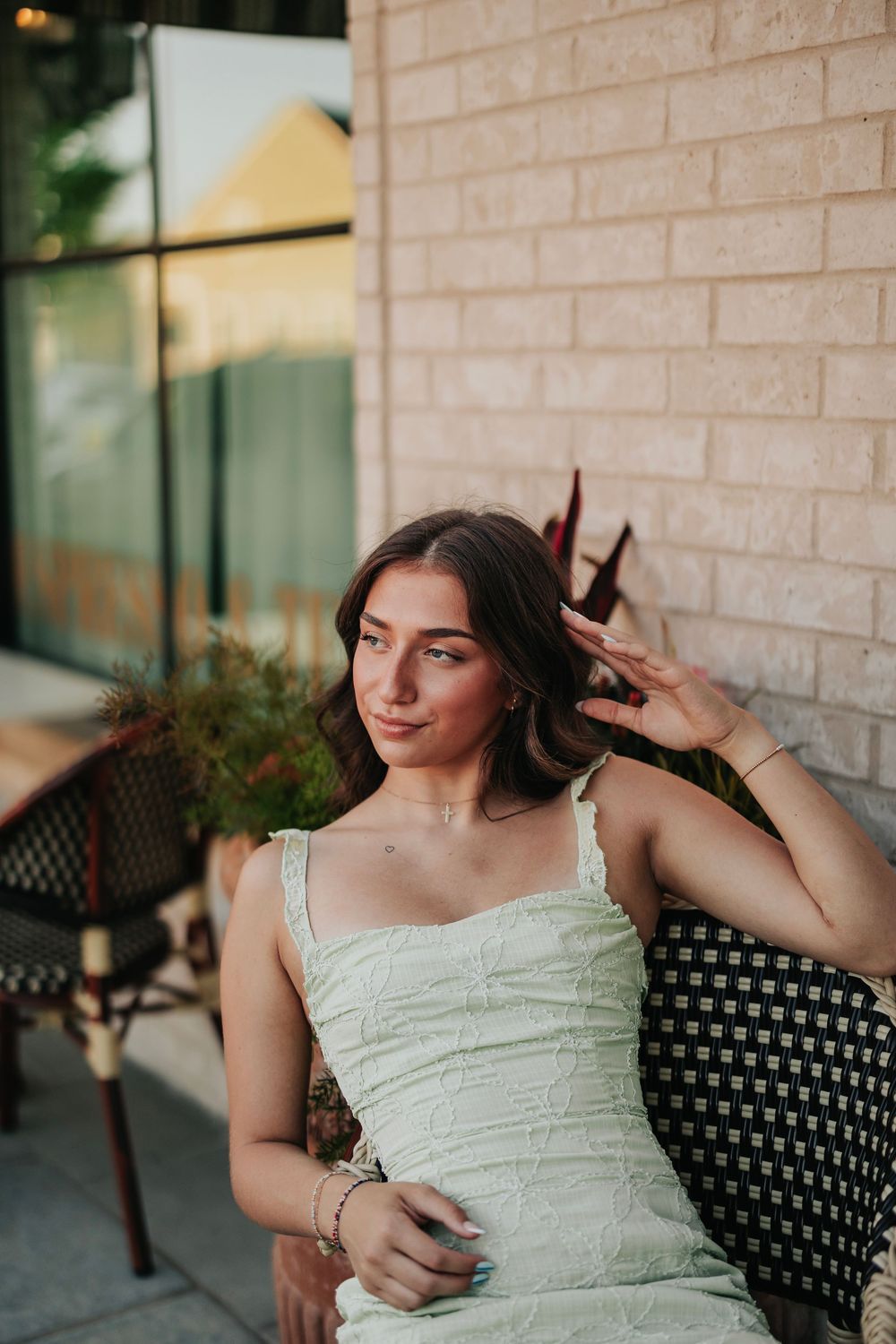 Outdoor portrait session against brick wall in light summer dress.