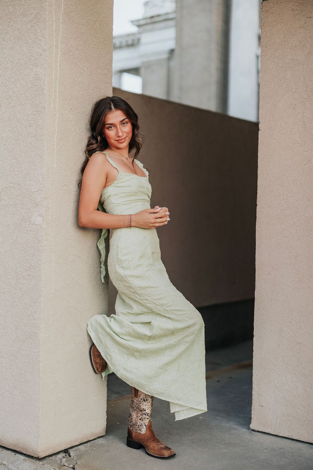 Artistic poses captured against neutral walls showcase a pale yellow dress and western boots.