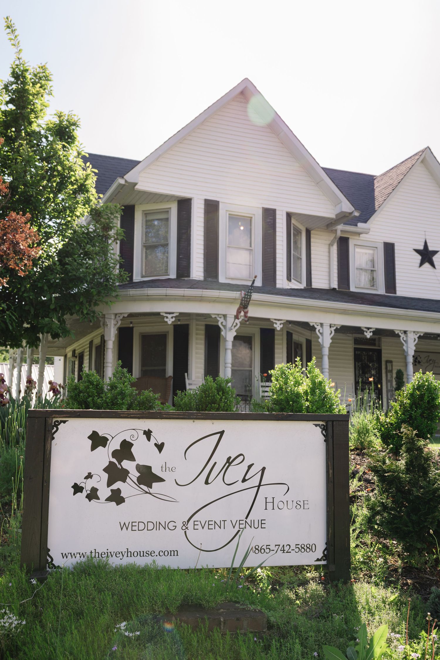White wedding venue house with black trim and business signage displaying 'The Ivy House' for events and ceremonies.