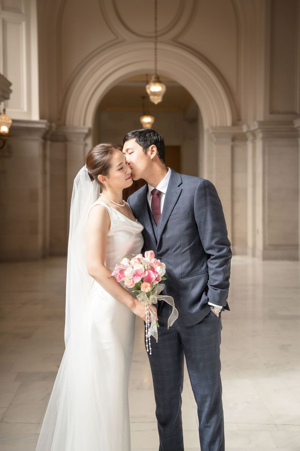 A romantic wedding photo series showing tender moments between newlyweds in a classic architectural setting.
