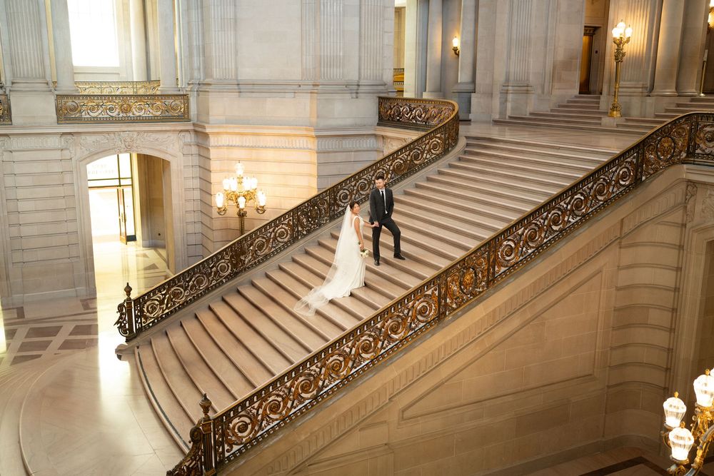 Elegant marble staircase with ornate gold railings and warm lighting in San Francisco City Hall.