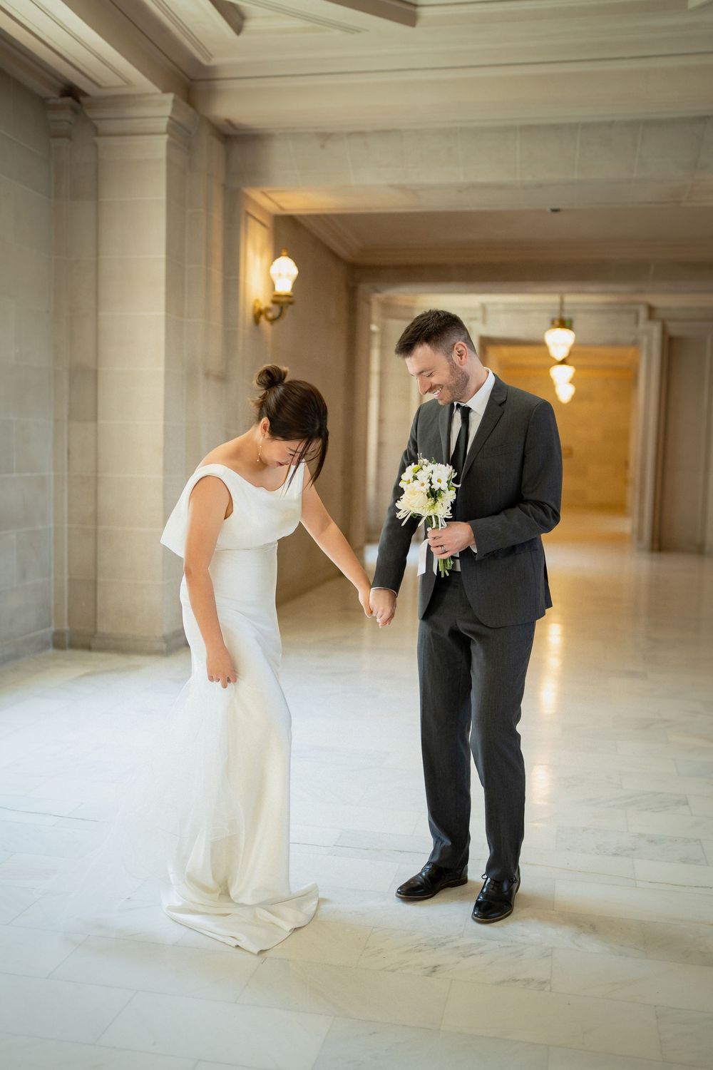 A couple dances and twirls in an elegant marble-floored government building hallway.