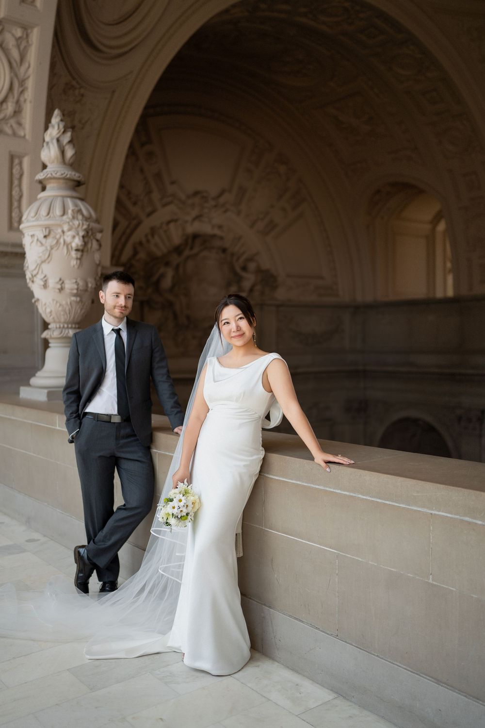 Wedding portraits taken along ornate stone balcony with decorative architectural details.