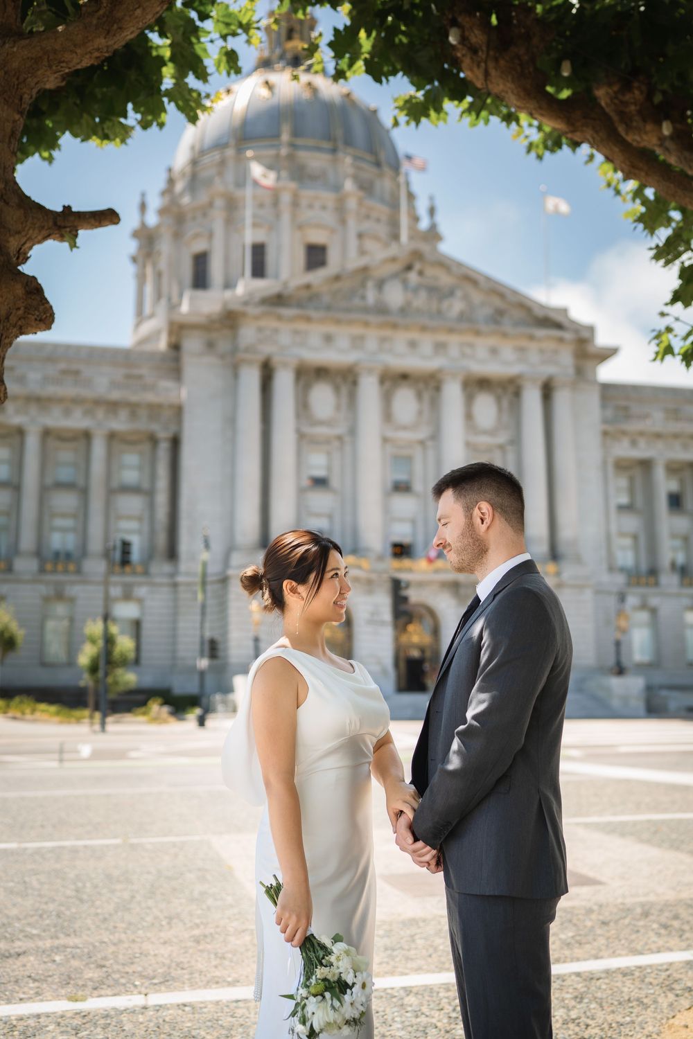 A couple shares intimate moments outside San Francisco City Hall with its domed architecture in the background.